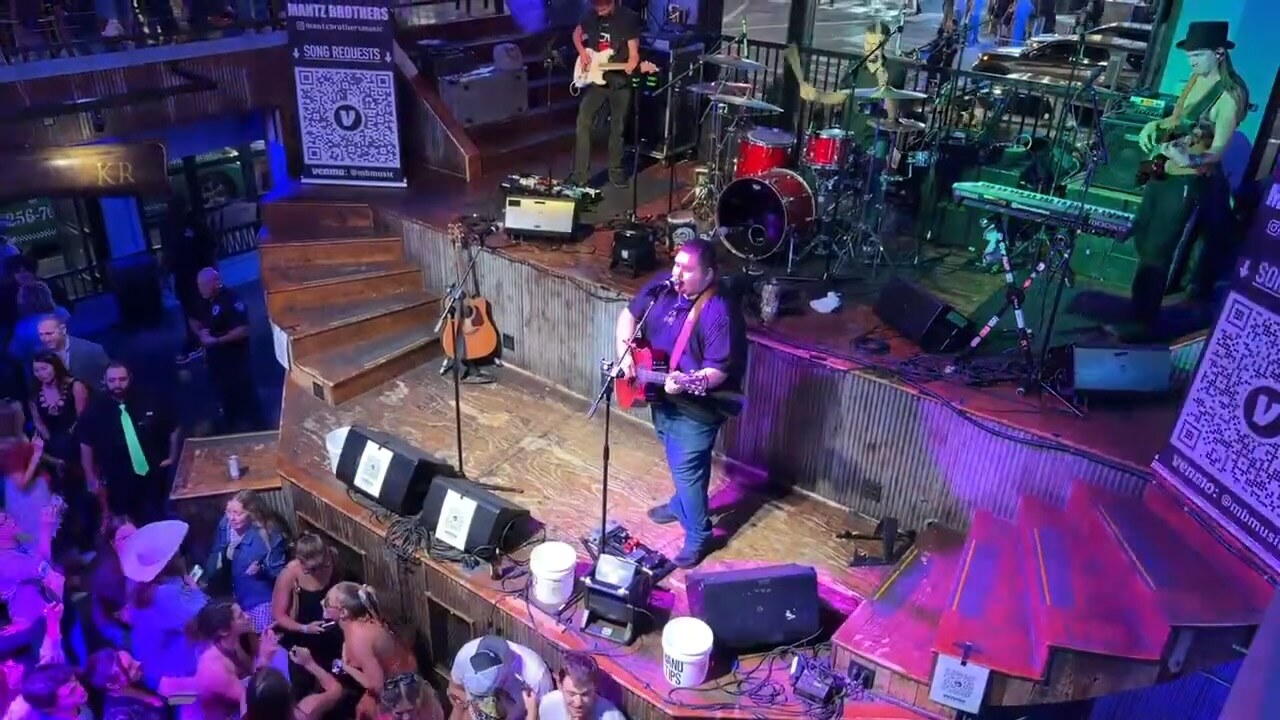 Jayce Walsh performing acoustic guitar for a crowd in Nashville