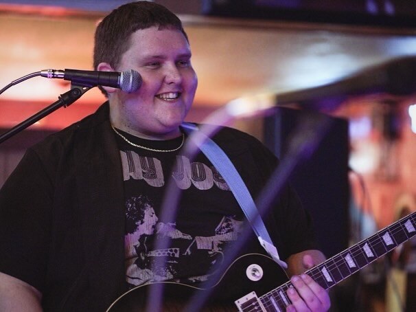 Jayce Walsh smiling while playing a Gibson Les Paul